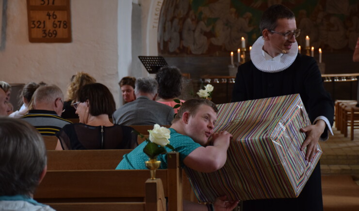 Præst holder stor papkasse i kirke