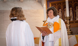 Biskop og præst står overfor hinanden i kirke